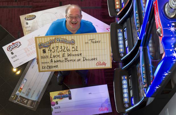 E.J. Coyle, a project manager at Bally Technologies, poses with oversized checks at the company lobby Thursday, Nov. 14, 2013. Coyle is a member of the Jackpot Response Team. A member is always on call in the event that a gambler hits a progressive jackpot on a Bally Technologies slot machine.