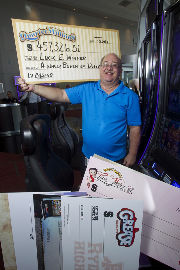 E.J. Coyle, a project manager at Bally Technologies, poses with oversized checks at the company lobby Thursday, Nov. 14, 2013. Coyle is a member of the Jackpot Response Team. A member is always on call in the event that a gambler hits a progressive jackpot on a Bally Technologies slot machine.