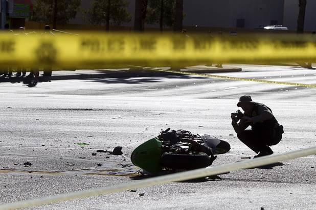 A Metro Police crime scene analyst takes a photos at a fatal motorcycle accident at the intersection of Flamingo and Lindell roads Thursday, Nov. 14, 2013.