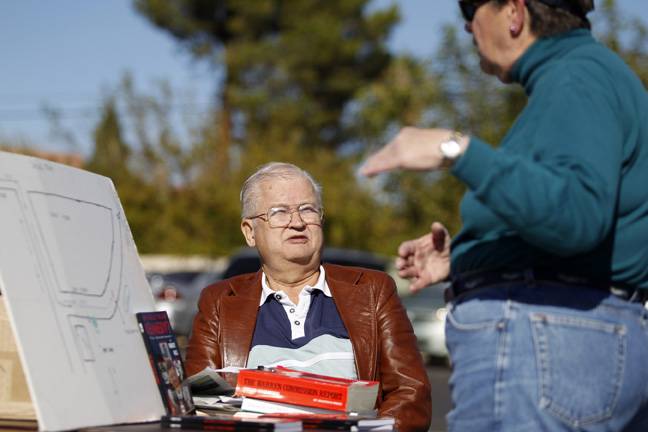 Las Vegas resident and Kennedy assassination conspiracy theorist Bob Ries talks to a shopper while selling his book "Who Really Killed Kennedy?" at a church garage sale Saturday, Nov. 2, 2013.