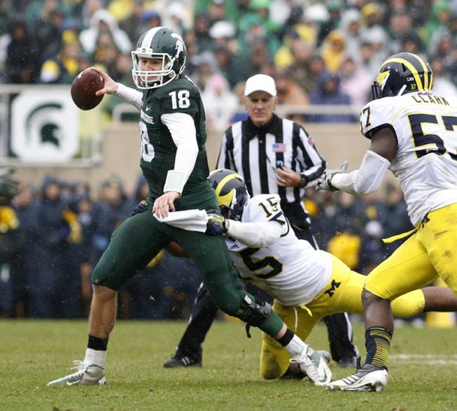 Michigan State quarterback Connor Cook (18) is stopped as he scrambles by Michigan's James Ross III (15) and Frank Clark (57) during the second quarter of an NCAA college football game, Saturday, Nov. 2, 2013, in East Lansing, Mich. 