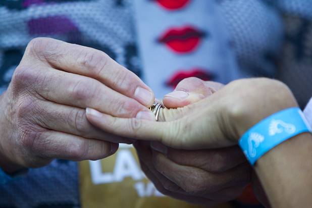 Paul Cote, center, of New York City puts a ring on his wife's finger as they marry during the 5th annual Rock 'n' Roll Las Vegas Marathon Sunday, Nov. 17, 2013. The Cotes were among the couple who married at the marathon.