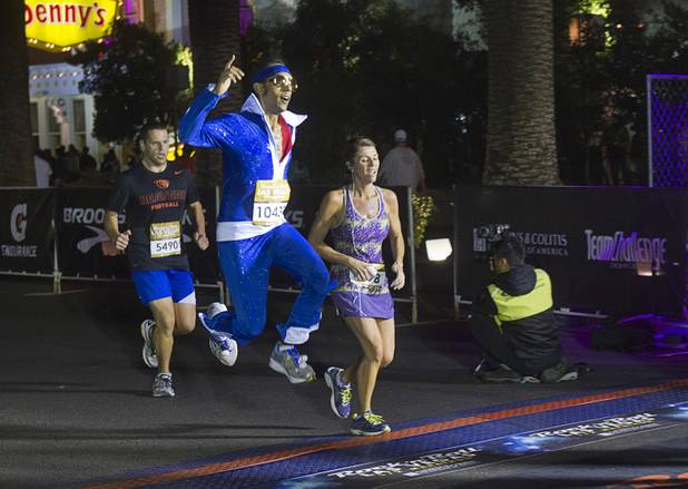 A runner wearing an Elvis Presley costume jumps over the half-marathon finish line during the 5th annual Rock 'n' Roll Las Vegas Marathon Sunday, Nov. 17, 2013.
