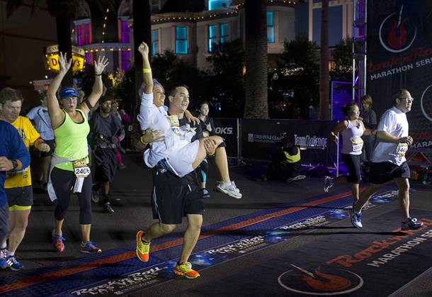 Tommy Welch, of Los Angeles, carries his wife Karla Torres-Welch over the half-marthon finish line during the 5th annual Rock 'n' Roll Las Vegas Marathon Sunday, Nov. 17, 2013. The couple renewed their wedding vows before the run.