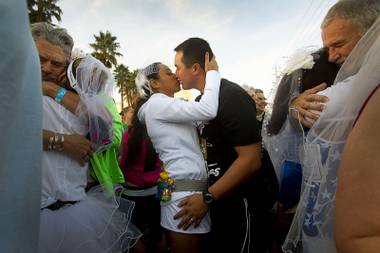 Tommy Welch and his wife Karla Torres-Welch of Los Angeles kiss during a mass ceremony for couples marrying and renewing their vows at the 5th annual Rock ‘n’ Roll Las Vegas Marathon Sunday, Nov. 17, 2013. 