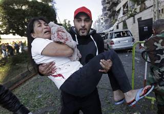 A Lebanese man carries an injured Asian domestic worker, at the scene where two explosions have struck near the Iranian Embassy killing many, in Beirut, Lebanon, Tuesday Nov. 19, 2013. 