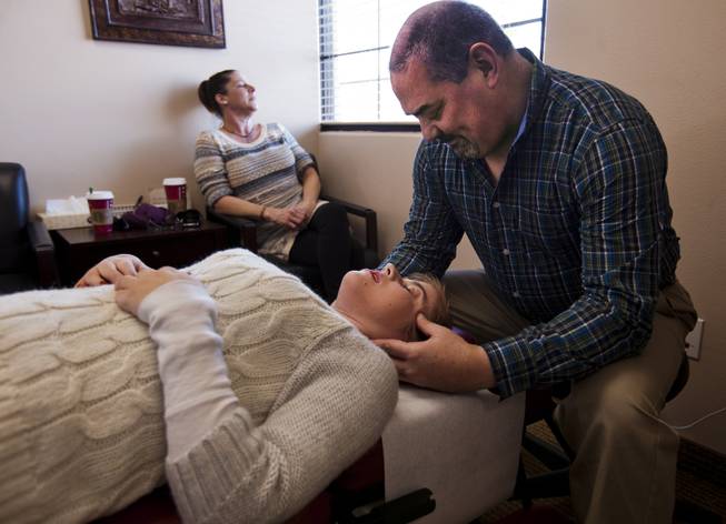 Jenny Stiles has her sinuses checked by chiropractor Dr. Scott Wallace during a regular spine adjustment session due to her uneven leg lengths, her mom Karen waits for the start of her session in the background, Wednesday, Nov. 20, 2013.