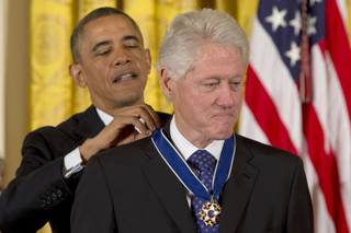 President Barack Obama awards former President Bill Clinton with the Presidential Medal of Freedom, Wednesday, Nov. 20, 2013, during a cermeony in the East Room of the White House in Washington. 