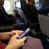 In this Oct. 31, 2013, file photo, a passenger checks her cellphone before a flight in Boston.