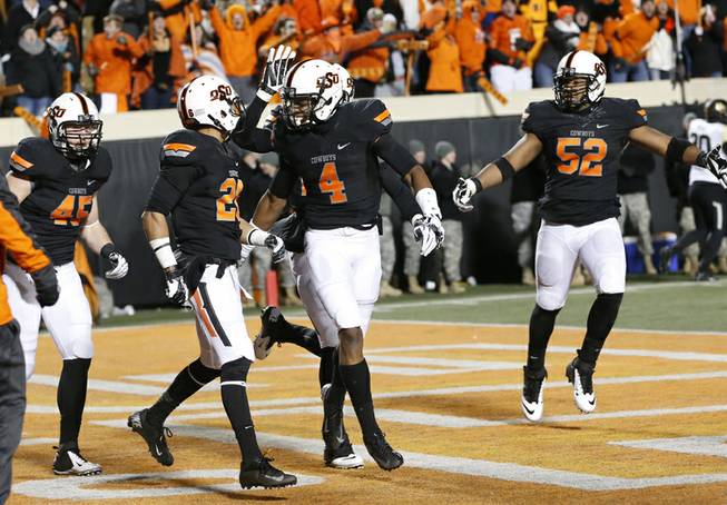Oklahoma State's Justin Gilbert (4) celebrates with teammate Tyler Patmon (26) following Patmon's touchdown against Baylor in the fourth quarter of an NCAA college football game in Stillwater, Okla., Saturday, Nov. 23, 2013. Oklahoma State won 49-17. 