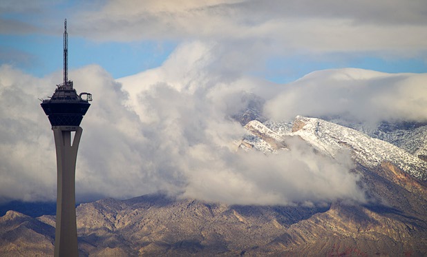 Low clouds and snow-covered mountains are seen behind the Stratosphere Tower Sunday, Nov. 24, 2013. 