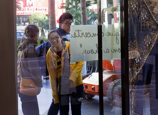 A woman peeks through a window as workers set up for "Too Much of a Good Thing Is Wonderful: Liberace and the Art of Costume" in the Cosmopolitan Monday, Nov. 25, 2013. The exhibit opened Monday and will run through Jan.1, 2014. Admission is free but any donations will benefit the Liberace Foundations scholarship fund.