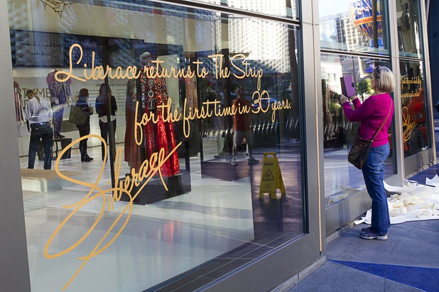 A woman takes a photo through a window prior to the opening of "Too Much of a Good Thing Is Wonderful: Liberace and the Art of Costume" in the Cosmopolitan Monday, Nov. 25, 2013. The exhibit opened Monday and will run through Jan.1, 2014. Admission is free but any donations will benefit the Liberace Foundations scholarship fund.