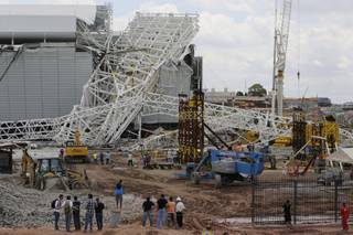 People stand in front of a metal structure that buckled on part of the Itaquerao Stadium in Sao Paulo, Brazil, Wednesday, Nov. 27, 2013. 