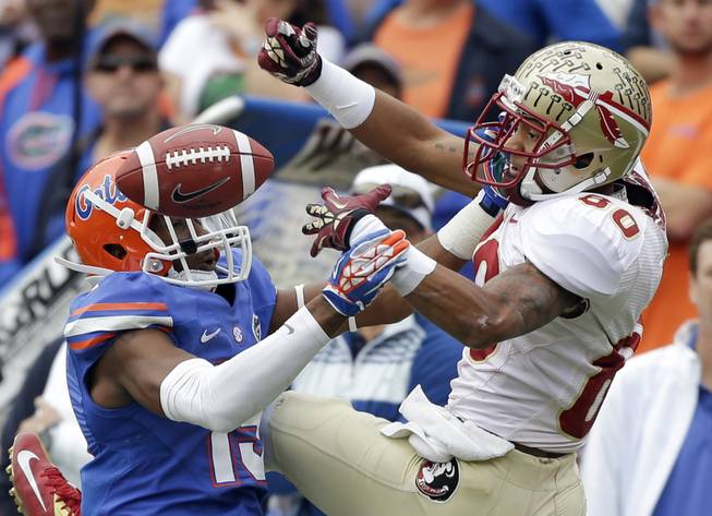 Florida defensive back Loucheiz Purifoy, left, breaks up and intercepts a pass intended for Florida State wide receiver Rashad Greene (80) during the first half of an NCAA college football game in Gainesville, Fla., Saturday, Nov. 30, 2013.