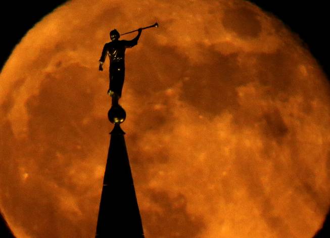 A statue of the Angel Moroni on top of a Latter-day Saints temple is silhouetted against the rising full moon, Monday, Nov. 18, 2013, in Kansas City, Mo.
