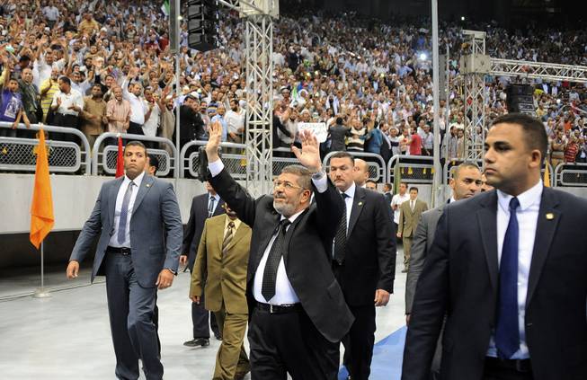 Egyptian President Mohammed Morsi waves as he arrives at a rally called for by hardline Islamists loyal to the Egyptian president to show solidarity with the people of Syria, in a stadium in Cairo, Egypt, June 15, 2013. 