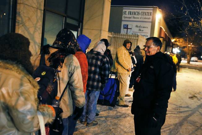 Before dawn and in -9 degree weather, Tom Tuning, right, greets men who wait for the opening of the St. Francis Center's day shelter, where Tuning is finance director, in downtown Denver, Thursday Dec. 5, 2013. A wintry storm pushing through the western half of the country has brought bitterly cold temperatures that prompted safety warnings for residents in the Rockies and threatened crops as far south as California.