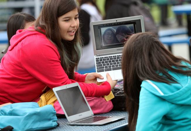 Pinacate Middle School student Melissa Lopez, 12, left, holds her Chromebook up so that Jasmin Cadenes, 12, can see it at their lunch table, Dec. 6, 2013, in Perris, Calif.