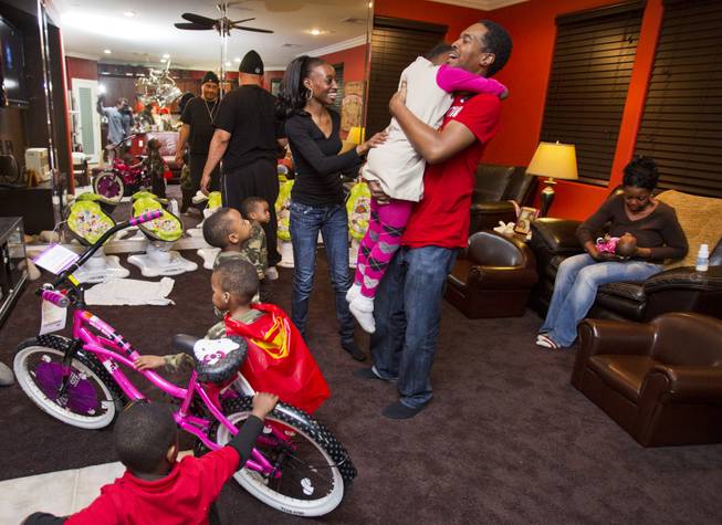 Darian Derrico, 8, is moved to tears in the arms of her father, Deon, after receiving a new bicycle during her birthday party on Monday, Dec. 9, 2013.