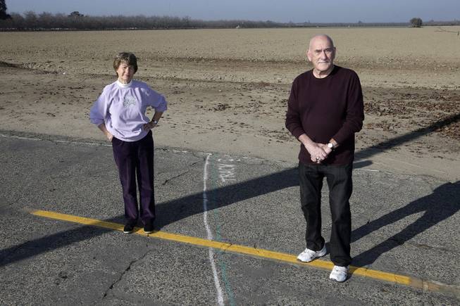 Phyllis and Ross Browning stand alongside a line drawn across Cairo Avenue marking the path of the proposed high-speed rail through their Hanford, Calif., neighborhood, Dec. 12, 2013. The proposed rail line will run a few houses away from their residence. The couple moved to Hanford in 2005 to retire and live next door to Phyllis' mother.