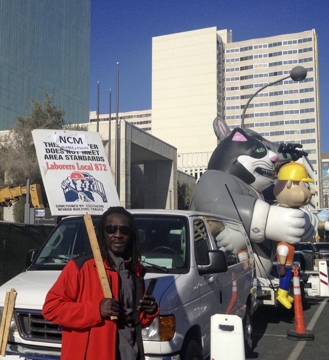 A protestor stands in front of an inflated rat and cat holding a construction worker stand vigil at the old Clark County courthouse, 200 S. 3rd St Thursday, Dec. 12, 2013.