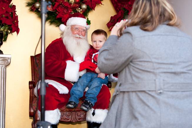 Landon Harrison, 2, looks a bit uneasy while his mom, Melissa, takes a photograph of him with Santa Claus in his cottage at Tivoli Village in Las Vegas Friday, December 13, 2013.  Larry Hansen has been donning the coveted suit and sharing the spirit of Santa for over nine years in Las Vegas.