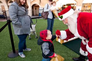 Landon Harrison, 2, gives Santa a high five after visiting him in his cottage at Tivoli Village in Las Vegas Friday, December 13, 2013.  Larry Hansen has been donning the coveted suit and sharing the spirit of Santa for over nine years in Las Vegas.