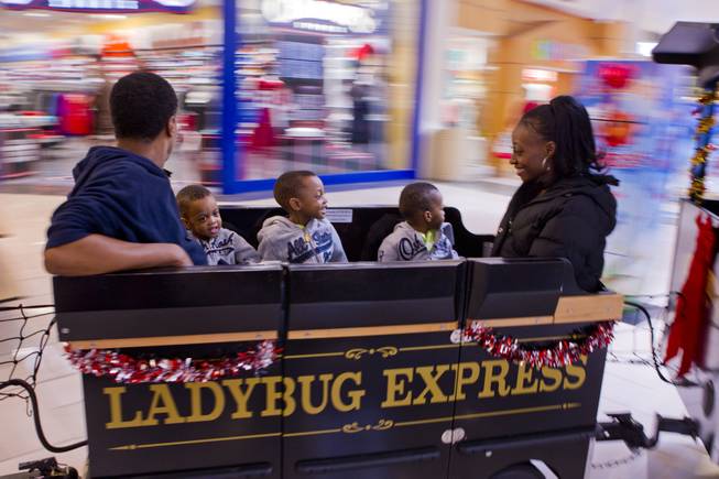 Deon and Evonne Derrico ride the Ladybug Express with their sons during a Christmas shopping trip to the mall Friday, Dec. 13, 2013.