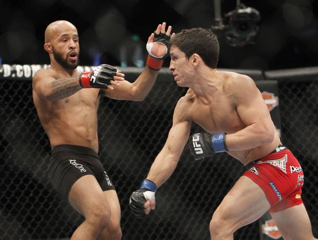 Demetrious Johnson, left, avoids a punch from Joseph Benavidez in a UFC flyweight mixed martial arts title fight in Sacramento, Calif., Saturday, Dec. 14, 2013. 