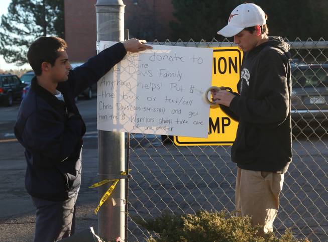 Michael Vartuli, left, and Chris Davis, both seniors at Arapahoe High School, hang a sign Saturday, Dec. 14, 2013, asking for donations to help the family of Claire Esther Davis, 17, the girl who was wounded in the school shooting the previous day in Centennial, Colo.