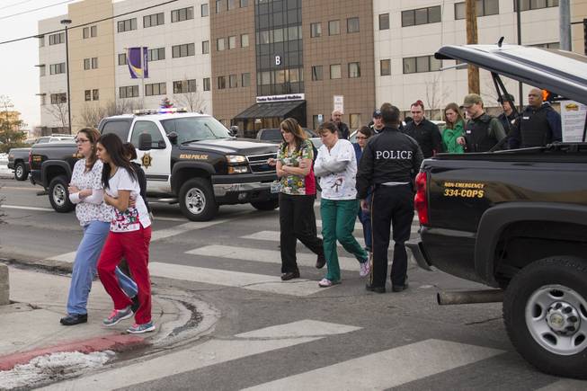 Officers escort witnesses to a bus at the Renown Regional Medical Center after a lone gunman shot and injured four people before killing himself , Tuesday, Dec. 17, 2013 in Reno, Nev.
