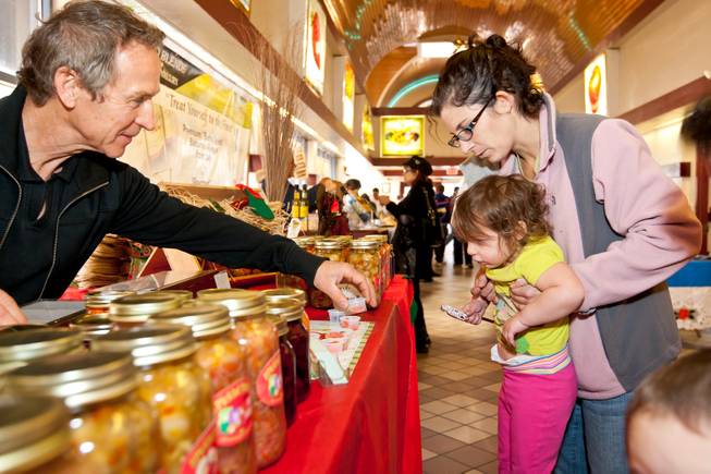 Nick Kreway offers pickled carrots to two-year-old Sophie Meza and her mom, Laura, while selling his pickled products from The Pickled Pantry booth at the Downtown Farmers' Market in Las Vegas Friday, December 20, 2013.