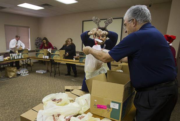 Arizona Charlie's employee Debbi Lewis holds a turkey for Ron Lurie as they pack holiday food boxes at the Boulder Highway location Monday, Dec. 23, 2013. Casino patrons contributed loyalty card points to the Feed a Family program and bought holiday dinners for 60 families. The food baskets will be picked up by the Southern Nevada Regional Housing Authority for distribution to needy families.