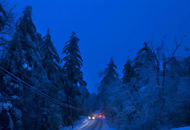 Utility crews prepare to work on power lines at dusk, Thursday, Dec. 26, 2013, in Litchfield, Maine, where many have been without electricity since Monday's ice storm.  Up to 7 inches of snow is forecast, worrying utilities that the additional weight on branches and transmission lines could cause setbacks in the around-the-clock efforts to restore power. 