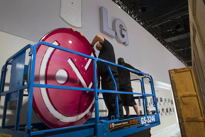 Workers prepare to hang the LG Electronics logo as they build a booth in preparation for the 2014 Consumer Electronics Show (CES) at the Las Vegas Convention Center Saturday, Jan. 4, 2014.