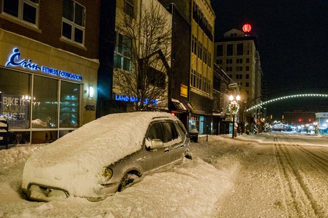 A vehicle sits snowed-in on Saginaw Street, early Monday, Jan. 6, 2014, in downtown Flint, Mich., where a recorded 16.2 inches of snow fell. Michigan residents braced Monday for temperatures to dive further to dangerously cold levels as they dug out following a multi-day storm that shuttered schools and government offices across the state.