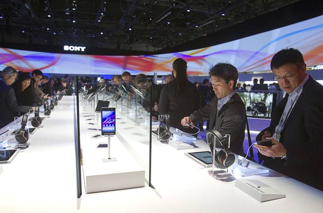 People look over headphones and Xperia Z1s smartphones at the Sony booth during the 2014 International Consumer Electronics Show (CES) in Las Vegas, Tuesday Jan. 7, 2014.