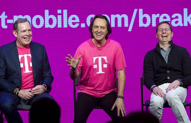 T-Mobile executives (L-R) CFO Braxton Carter, CEO John Legere, and CMO Mike Sievert, react to a question during a news conference at the 2014 International Consumer Electronics Show (CES) in Las Vegas, Jan. 8, 2014. T-Mobile announced it will pay Early Termination Fees (ETF) for families who transfer service from AT&T, Verizon, and Sprint.