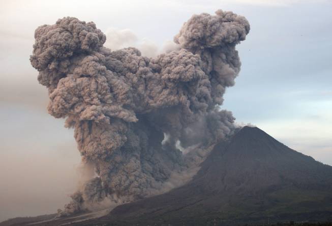 Mount Sinabung spews volcanic materials as seen from Gundaling, North Sumatra, Indonesia, Wednesday, Jan. 8, 2014. The volcano has sporadically erupted since September, forcing thousands of people who live around it slopes to flee their homes. 