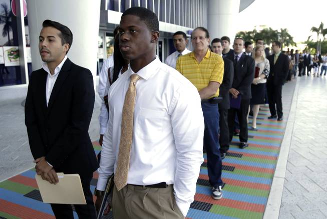In this Wednesday, Oct. 23, 2013, file photo, Luis Mendez, 23, left, and Maurice Mike, 23, wait in line at a job fair held by the Miami Marlins, at Marlins Park in Miami. The labor Department issues the December jobs report, the last one for 2103, on January 10, 2014.