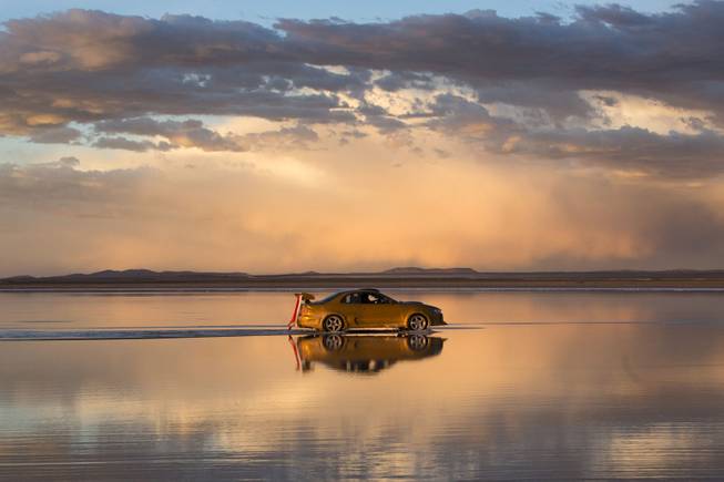 The sky is reflected on the Uyuni Salt Flats as a car drives by in Uyuni, Bolivia,  Saturday, Jan. 11, 2014. The motorcycles and quads of the Dakar Rally will race through parts of the Uyuni Salt Flats on Jan. 13, 2014.