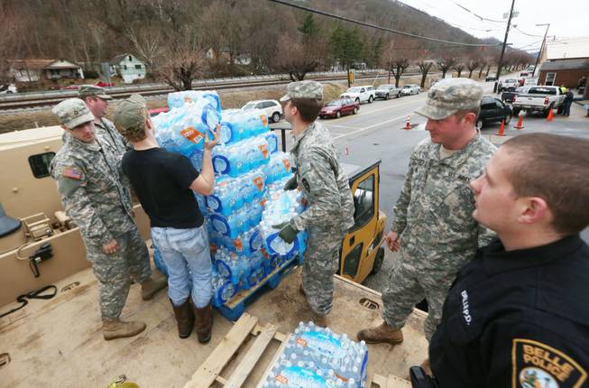 Members of the West Virginia Army National Guard, along with a member of the Belle Police Department and a volunteer, offload emergency water from a military truck to a forklift as citizens line up for water at the Belle Fire Department, Saturday, Jan. 11, 2014, in Belle, W.Va.