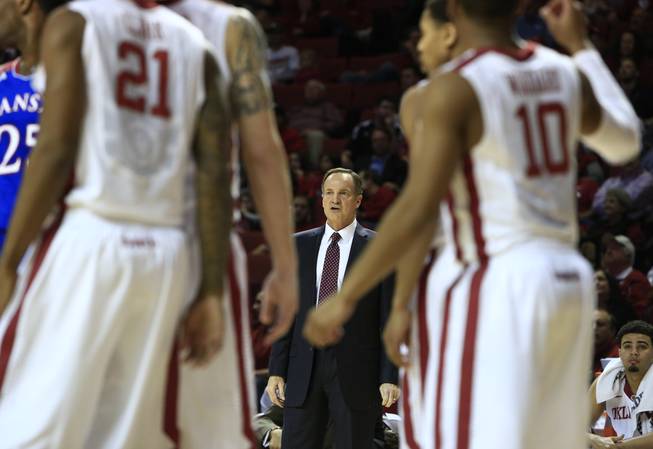 Oklahoma head coach Lon Kruger, center, watches as his team plays against Kansas during the first half of an NCAA college basketball game in Norman, Okla., Wednesday, Jan. 8, 2014. Kansas won 90-83.