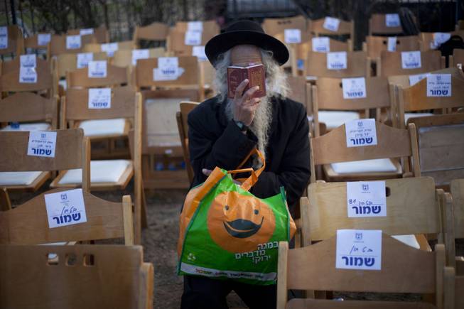 An ultra-Orthodox Jewish man reads from a payer book next to the grave of late Israeli Prime Minister Ariel Sharon, at the family farm near Sderot, southern Israel, Monday, Jan. 13, 2014. 