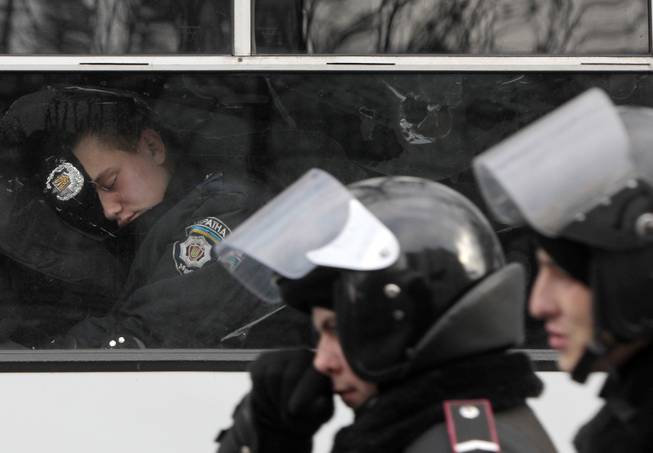 A police officer sleeps in a police van near of the Ukrainian Parliament in Kiev, Ukraine, in Kiev, Ukraine, Tuesday, Jan. 14, 2014. Organizers of the weeks-long anti-government protests are looking for a future strategy amid dwindling numbers and a continuing government crackdown on the protesters. The demonstrations, known as Euromaidan, were sparked by President Viktor Yanukovych's decision in November to freeze ties with the West and tilt toward Moscow. The pact was later sealed by a $15 billion bailout loan from the Kremlin. 