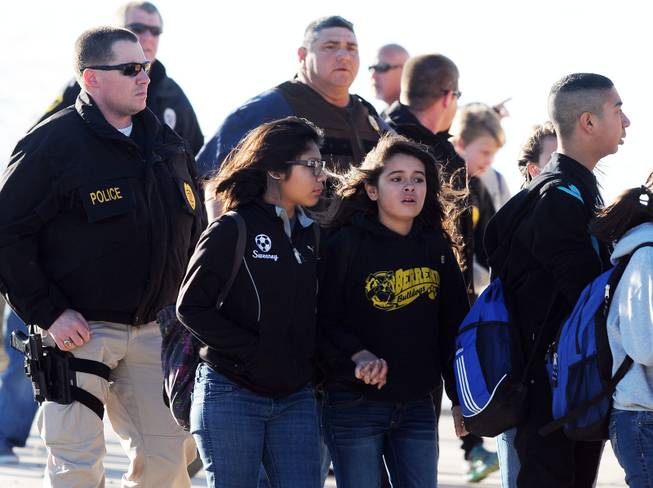 Students surrounded by officials are escorted from Berrendo Middle School after a shooting, Tuesday, Jan. 14, 2014, in Roswell, N.M.