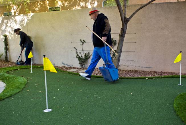 Curtis Murphy of Klean Scoop follows his fiance Melodie Harris as they clear a yard of dog poop that's complete with a putting green on Wednesday, Jan. 15, 2014.