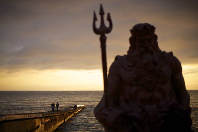 In this photo taken on Thursday, Nov. 28, 2013, the statue of ancient Roman god Neptune sits in guard of the beach during the sunset at an embankment of Sochi, Russia.