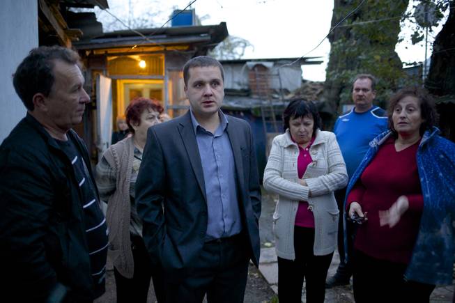In this photo taken on Wednesday, Nov. 27, 2013, Igor Zarytovsky, center, and his father Vladimir, left, gather with their neighbors in the yard of the railroad house in the village of Vesyoloye outside Sochi, Russia.
